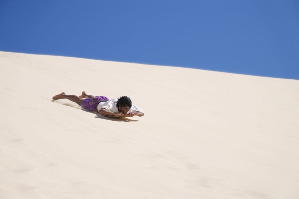 man sand boarding sand dune