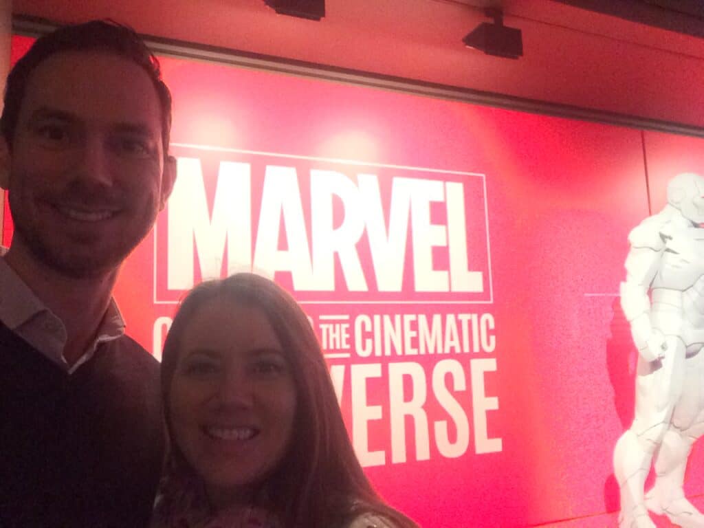 A man and a woman standing in front of an art exhibit of Marvel Cinematic Universe