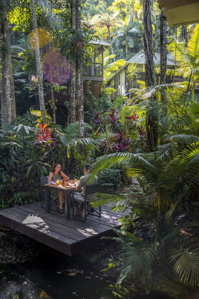 a couple dining on a table in lush rainforest landscaping in a resort