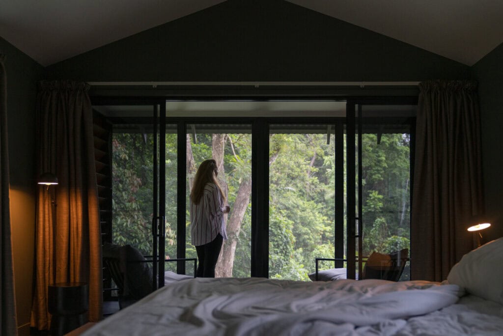 view of woman on balcony from room in tree canopy