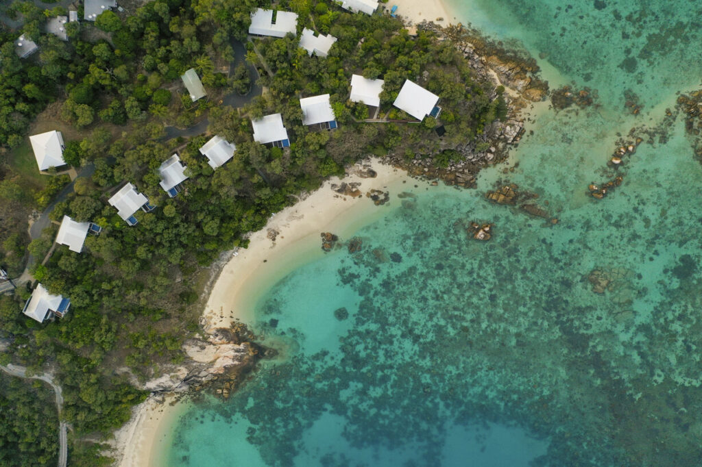 aerial view of luxury cabins nestled in rainforest on an island at great barrier reef