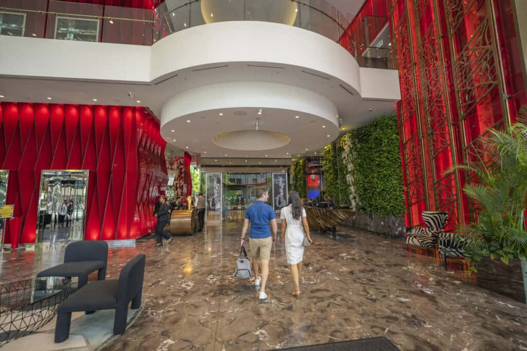 couple walking into hotel lobby with boutique red panels and wall gardens