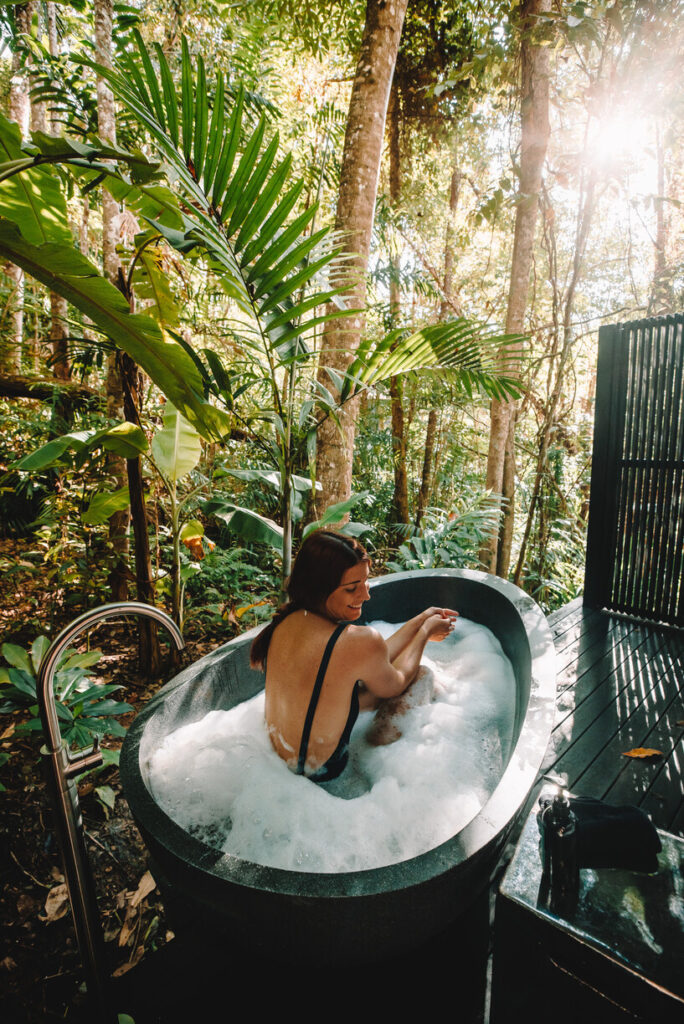 Lady relaxing in the outdoor bath of her Treehouse Retreat