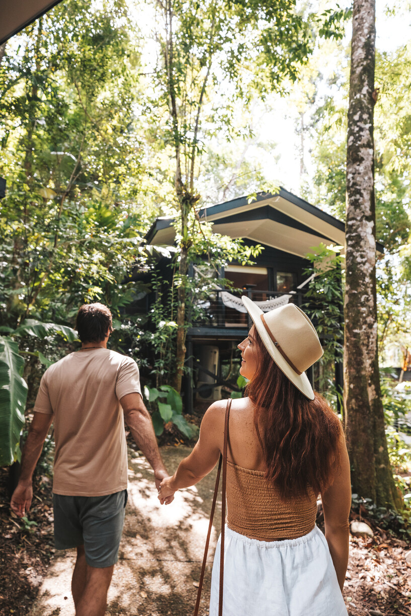couple walking along path toward hotel room amidst rainforest
