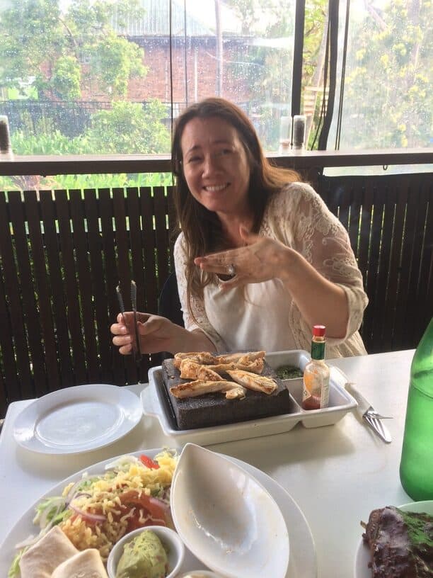 woman eating lunch while cooking meat on hot stone